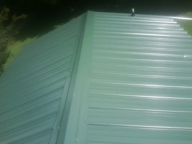 New green metal panels meeting at the ridge of a roof — Flat Roof Repair work by our crew in Ardmore