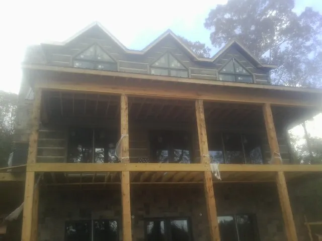 Dormers and porch framing on a large log home under construction — Roof Coating work by our crew in Ardmore