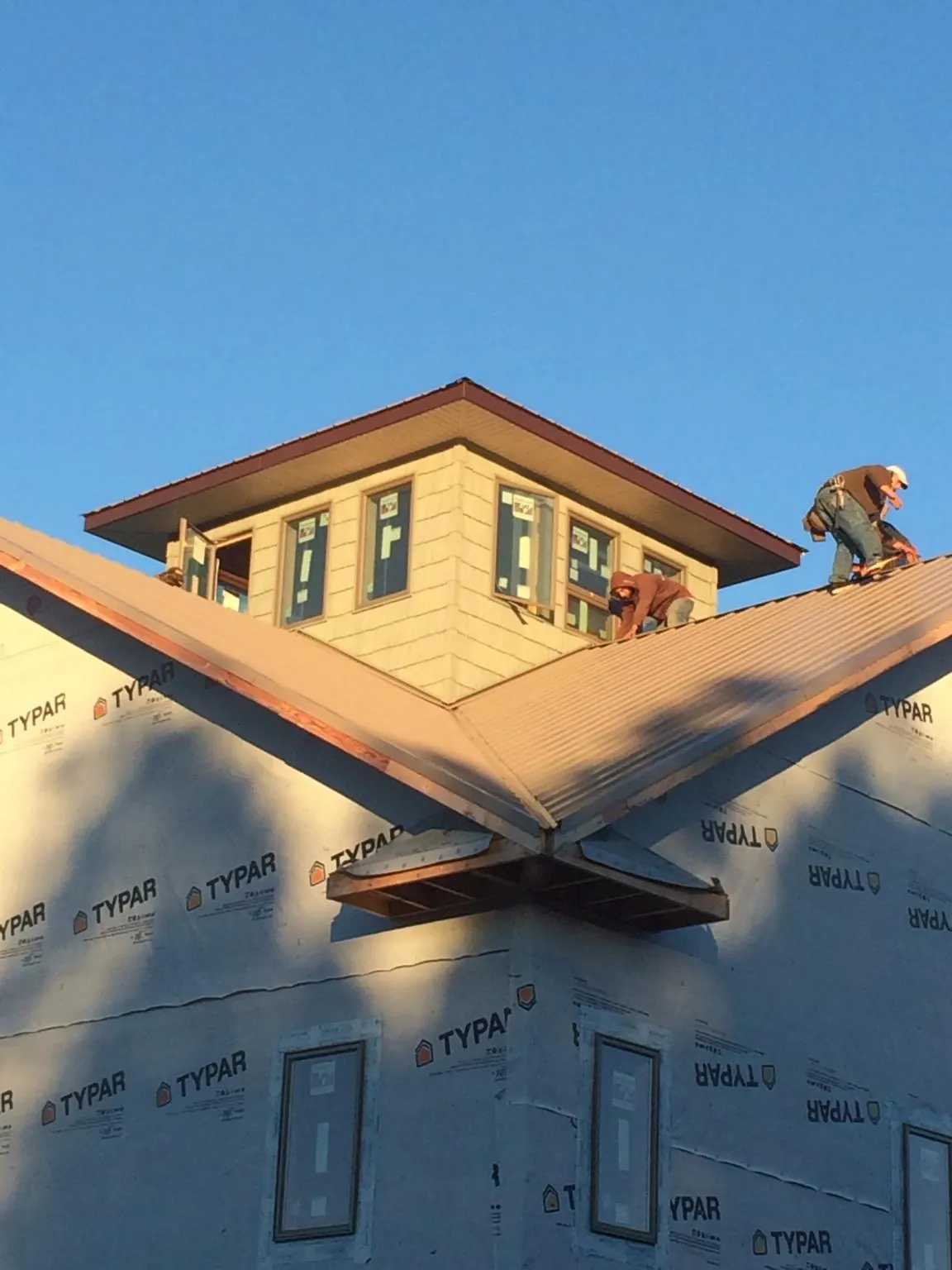 Roofers working around a rooftop cupola on a new metal roof at sunset — Roof Waterproofing in Ardmore by Roofing Brothers